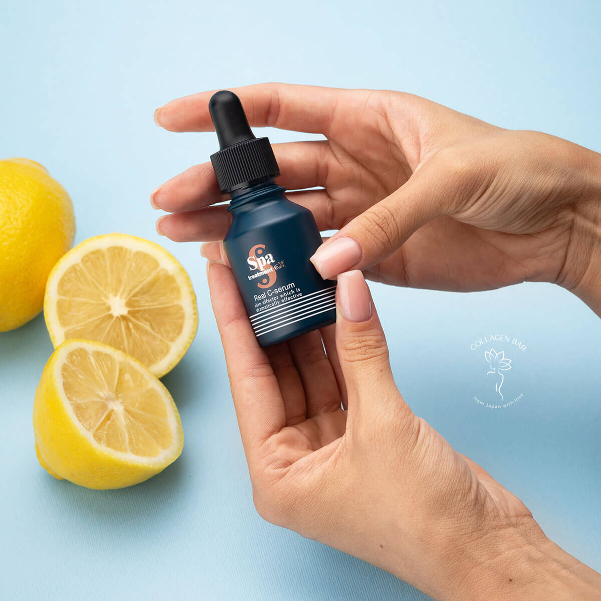 Флакон із сироваткою Spa Treatment Real C-serum в доглянутих жіночих руках на тлі цілих і половинок лимонів